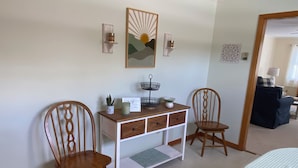A room with two wooden chairs, a white desk with drawers, a small plant, and a framed artwork on the wall. - Newly furnished ranch style home within 5 miles of Gore Mtn Ski Center (North Creek)