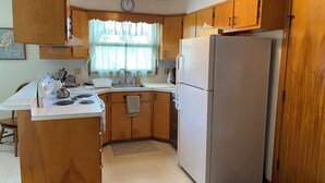A compact kitchen with wooden cabinets, a refrigerator, a stove, and a sink. - Newly furnished ranch style home within 5 miles of Gore Mtn Ski Center (North Creek)
