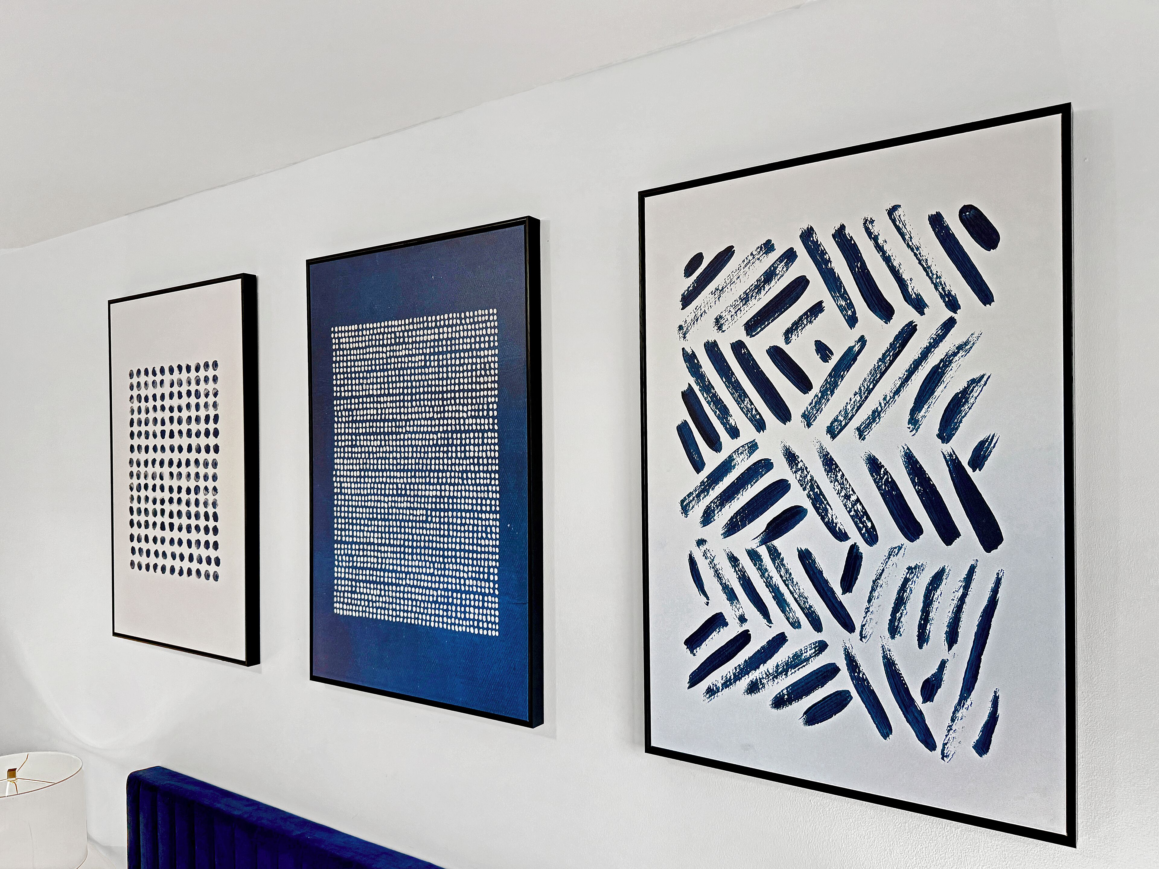 Tres obras de arte enmarcadas sobre una pared blanca.