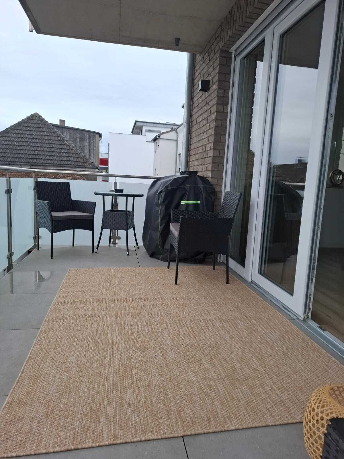A covered patio with a table and chairs, a grill, and a sliding glass door.