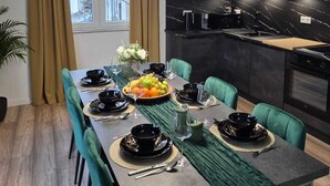 Un comedor moderno con una mesa larga, sillas verdes y una lámpara colgante contemporánea.