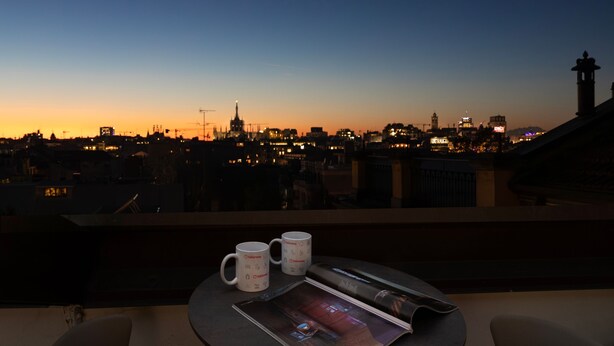 Un balcon avec deux tasses blanches, un magazine et une télécommande.