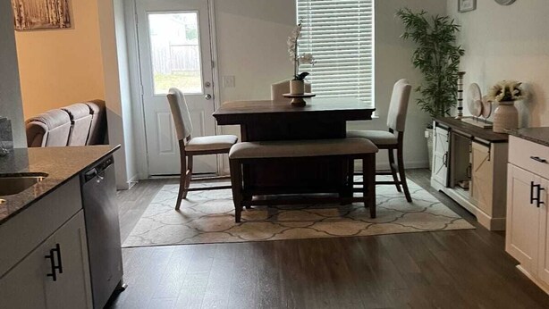 A modern kitchen with a dining area, featuring a central island, dark wood flooring, and a large window with blinds. - Charming 4-bedroom house with WiFi and AC in wonderful Spring (Spring)