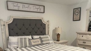 A bedroom with a bed, a nightstand, a dresser, and a framed sign on the wall. - Charming 4-bedroom house with WiFi and AC in wonderful Spring (Spring)