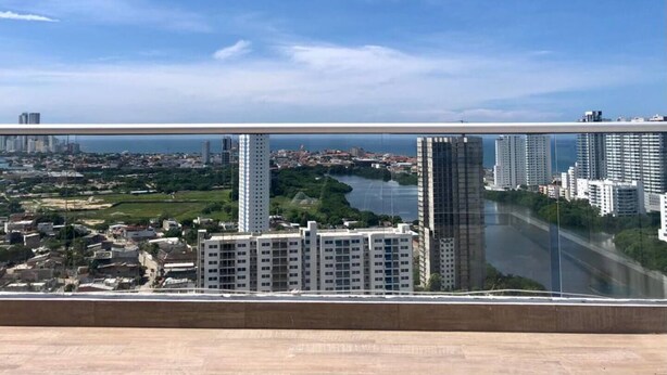 A high-rise building with a view of a river and a bridge in the background.