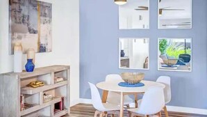 Zona pranzo con un tavolo rotondo, sedie bianche e una ventola a soffitto.