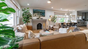 A spacious living room with a fireplace, a dining area, and a kitchen in the background. - Balboa Park, Zoo, Downtown! BRAND NEW (San Diego)