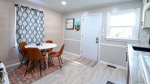 A compact kitchen with a white countertop, a door with a window, and a dining area with a round table and chairs.