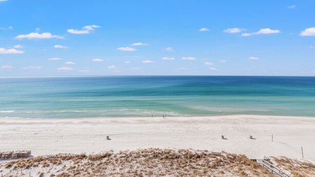 A beach with a clear sky, calm sea, and a sandy shore.