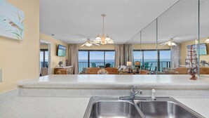 A kitchen with a large island, a ceiling fan, and a view of the ocean through large windows.