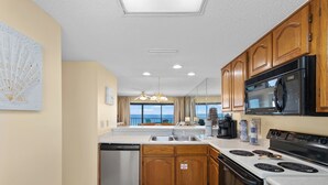 A modern kitchen with wooden cabinets, a built-in microwave, and a dishwasher.