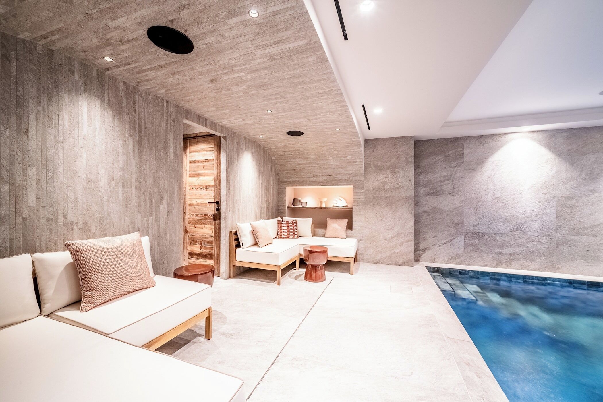 Un spa moderno con piscina, pared de madera y zona de estar con cojines.