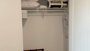 A walk-in closet with a wooden bench, white walls, and a wooden floor.