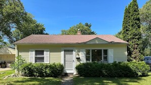 A single-story house with a front porch, a visible garage door, and a pathway leading to the entrance. - Cute and Cozy Near Parks (Midland)