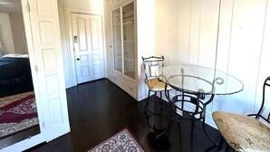 Una habitación con una mesa y sillas de vidrio, una puerta blanca y un armario con puertas de cristal.