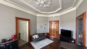 A living room with a sofa, a coffee table, a TV, and a fireplace. - Historical Studio Apt - Walk to All of Downtown (Bay City)
