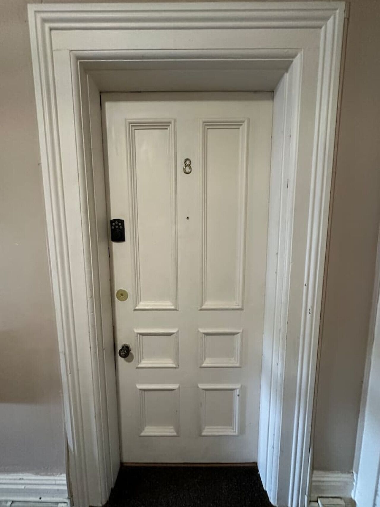 A white double door with a number 8, a keyhole, and a doorknob.