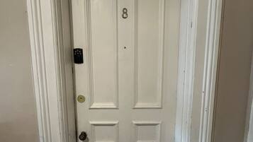 A white double door with a number 8, a keyhole, and a doorknob.