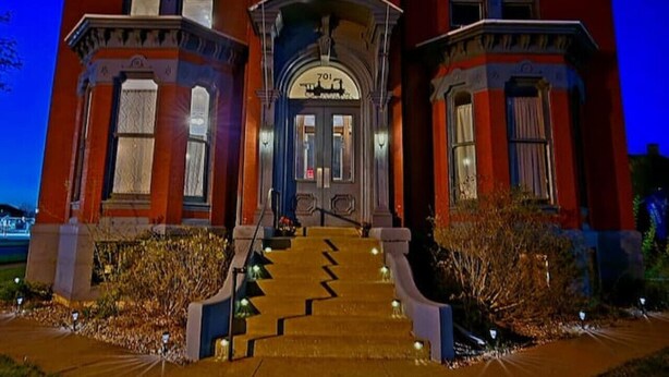 A large, red brick building with a grand entrance, multiple windows, and a staircase leading to the front door. - Historical Studio Apt - Walk to All of Downtown (Bay City)