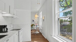 Una cocina moderna con armarios blancos, estufa integrada y una zona de comedor con mesa y sillas.