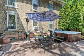 A patio with a table, chairs, a grill, and a hot tub. - Elizabeth`s Entire Apt @ Historic McCormick House (Bay City)