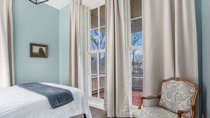 A bedroom with a bed, a chair, a window with curtains, and a framed picture on the wall. - Elizabeth`s Entire Apt @ Historic McCormick House (Bay City)