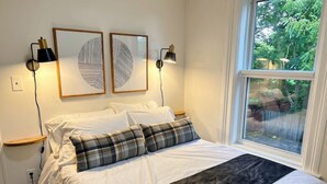 Ein Schlafzimmer mit einem Bett, zwei Wandleuchten und zwei gerahmten Kunstwerken.