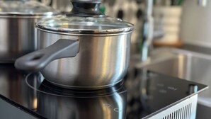 A stainless steel pot with a lid on an induction cooktop. - Fun & Functional Studio Apt (Bay City)