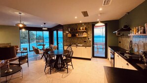 Une cuisine moderne avec vue sur la mer, un coin repas avec une table et des chaises, et une grande fenêtre.