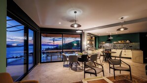 Une cuisine moderne avec vue sur la mer, un coin repas avec des chaises et une grande fenêtre.
