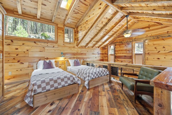 Une cabane avec deux lits en bois, une chaise verte et une table à manger.