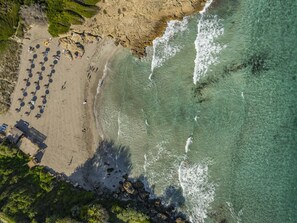 An aerial view of a beach with rows of umbrellas and a few structures. - Villa Marilen · Villa with private pool in Alcúdia (Alcúdia)
