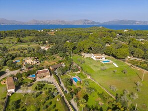 Un quartier résidentiel comprenant plusieurs maisons, une grande piscine et une vue sur la mer.