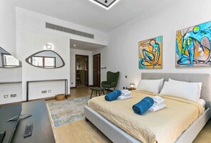 A modern hotel room with a large bed, a desk, and two abstract paintings on the wall. - Adjacent to Aphrodite Premium Apartments I (Kouklia)
