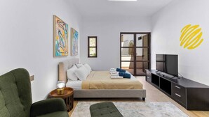 Une chambre à coucher moderne avec un lit, un téléviseur et des œuvres d’art accrochées au mur.