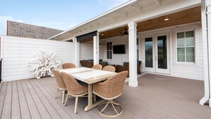 A covered patio with a wooden deck, a white exterior wall, and a large white table with wicker chairs. - Pet-Friendly Manor on Bourbon Trail, Pools, Golf Local Dining, Fully Loaded (Prospect)