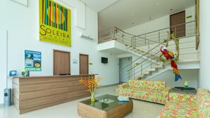 Un hall d’hôtel avec un comptoir d’accueil, un escalier et un canapé aux couleurs vives.