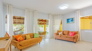 Ein geräumiges Wohnzimmer mit zwei Sofas, einem Essbereich und großen Fenstern mit Vorhängen.