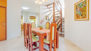 Ein Essbereich mit Holztisch und Stühlen, einer Chandelier, einer Treppe und einem Gemälde an der Wand.