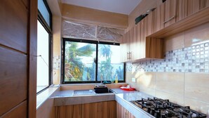 A modern kitchen with wooden cabinets, a large window, a gas stove, and a tiled backsplash. - Diani Luxe Villa (Diani Beach)