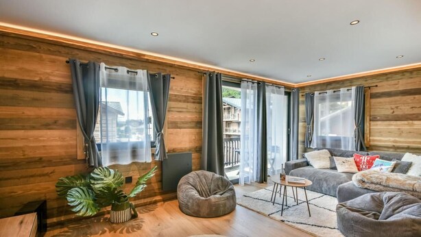 A modern living room with wooden walls, a sofa set, a coffee table, and a large plant.