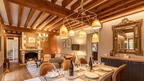 A dining area with a wooden ceiling, a fireplace, and a table set for a meal.