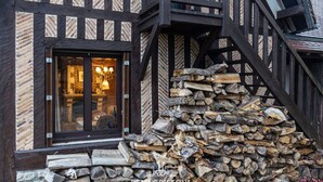 A timber-framed building with a large window and a stack of firewood outside.