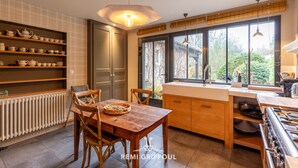 A modern kitchen with wooden furniture, a dining table, and a large window providing a view of the outdoors.