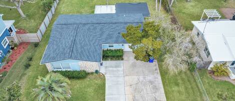 A residential property with a sloped roof, a front yard with a palm tree, and a driveway leading to the entrance.