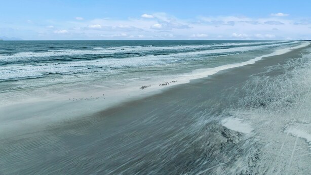 A beach with a wide sandy shore and gentle waves.