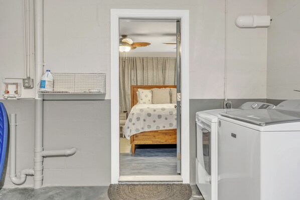 Un cuarto de lavandería con lavadora, secadora y un estante pequeño con una botella.