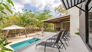 A modern outdoor pool area with lounge chairs, a covered seating area, and a pergola.