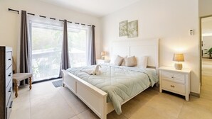 A bedroom with a bed, bedside tables, a nightstand, a chair, a dresser, and a window with curtains.
