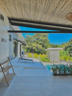 Un espacio al aire libre cubierto con piscina, sillas de descanso y una pérgola.